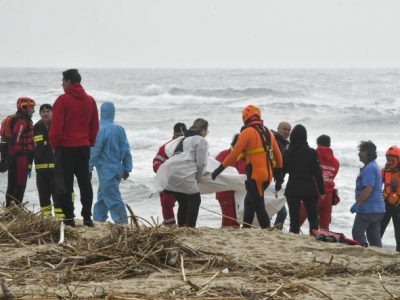 Rescuers recover a body at a beach near Cutro, southern Italy, after a migrant boat broke apart in rough seas, Sunday, Feb. 26, 2023. Rescue officials say an undetermined number of migrants have died and dozens have been rescued after their boat broke apart off southern Italy. (AP Photo/Giuseppe Pipita)